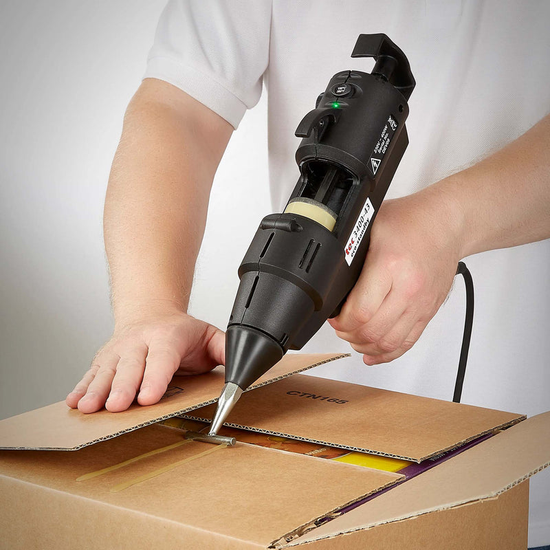 Worker sealing cardboard box using a hot glue gun